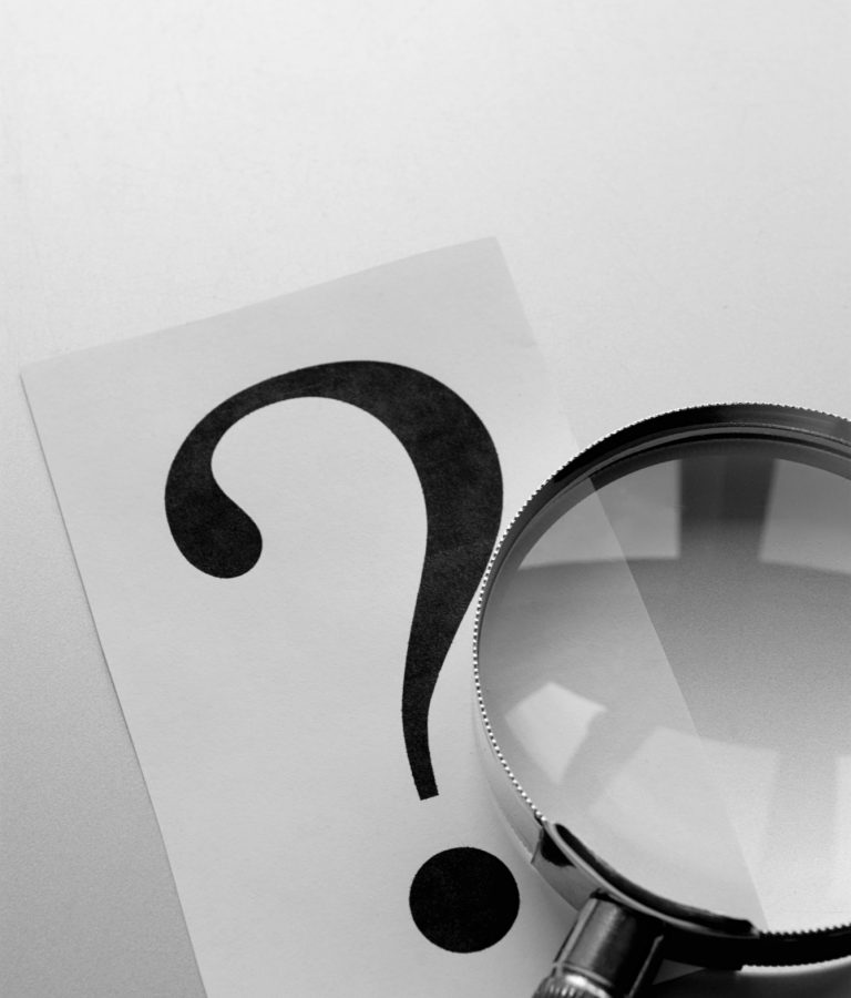 magnifying glass and a question mark on the paper